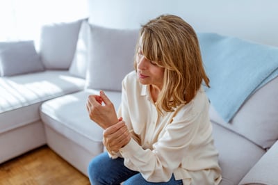 Mature woman grabbing wrist in pain from osteoporosis symptoms