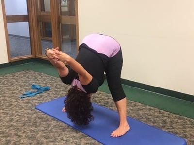 woman with advanced age performing restorative yoga such as this one, the Wide Legged Forward Bend, to relieve menopause symtoms 