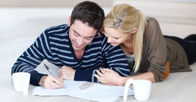 A couple planning their fertility journey together with paper and pen and coffee mugs