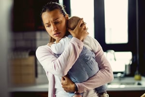 A new mom holding her baby with a worried or anxious look on her face that could be linked to postpartum mental health issues