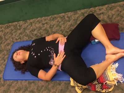 A menopausal woman practicing restorative yoga and doing the supta Baddha Konasana 2 pose to relieve menopause symptoms