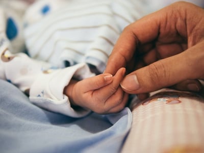a close up shot of a hand holding a newborn baby's hand