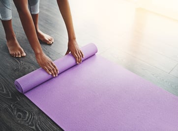 Woman laying out her yoga mat to do poses for period cramps