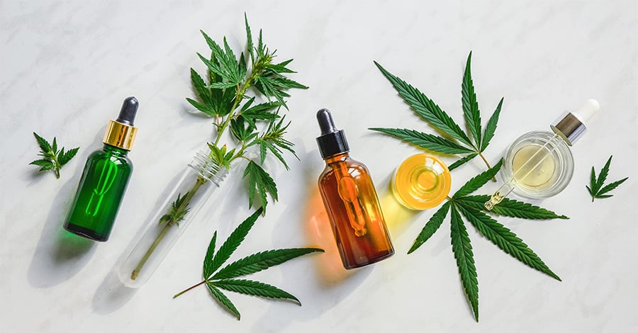 Various glass bottles with CBD oil, THC tincture and hemp leaves