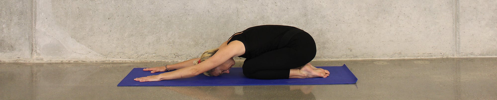 Woman doing the child's pose in yoga to relieve menstrual cramps