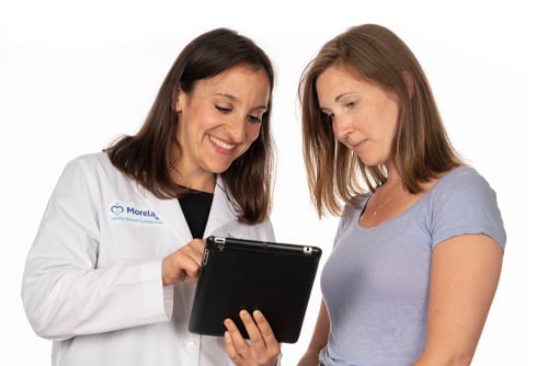 A women and her OBGYN discuss results gathered from a pelvic exam. Both doctor and patient are smiling and are engaged in a respectful and professional conversation. 