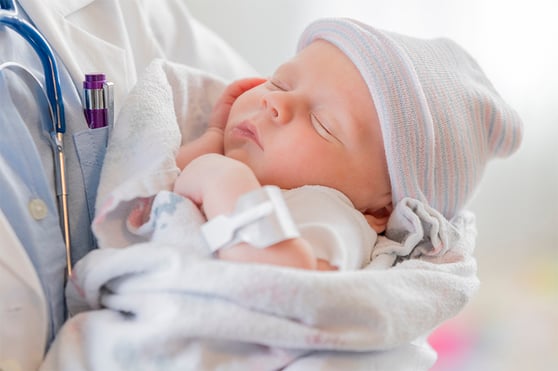 infant asleep in the arms of a pediatrician