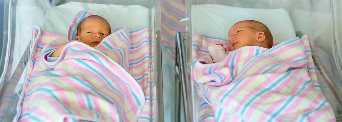 newborn twins boy and girl in hospital under blankets
