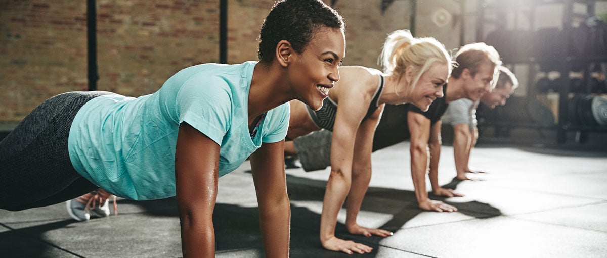 woman-smiling-while-doing-pushups-in-an-exercise-class